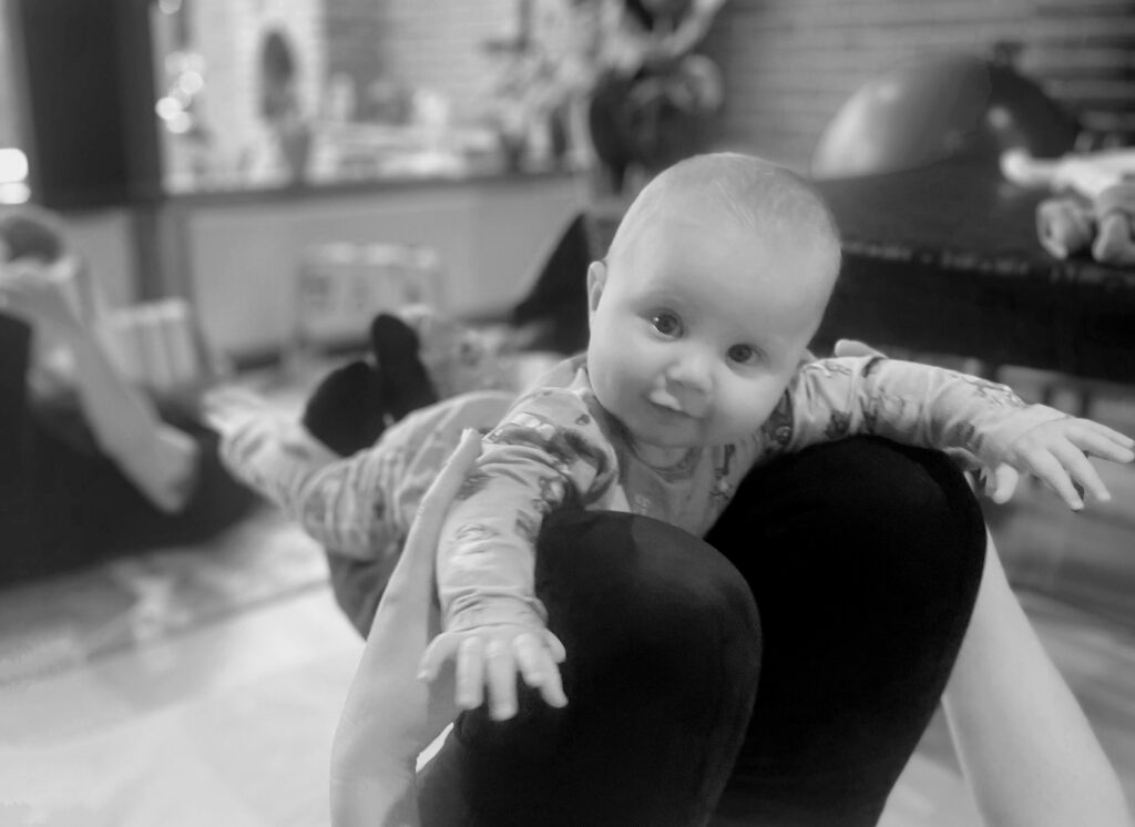 Baby ligger på voksens skinneben